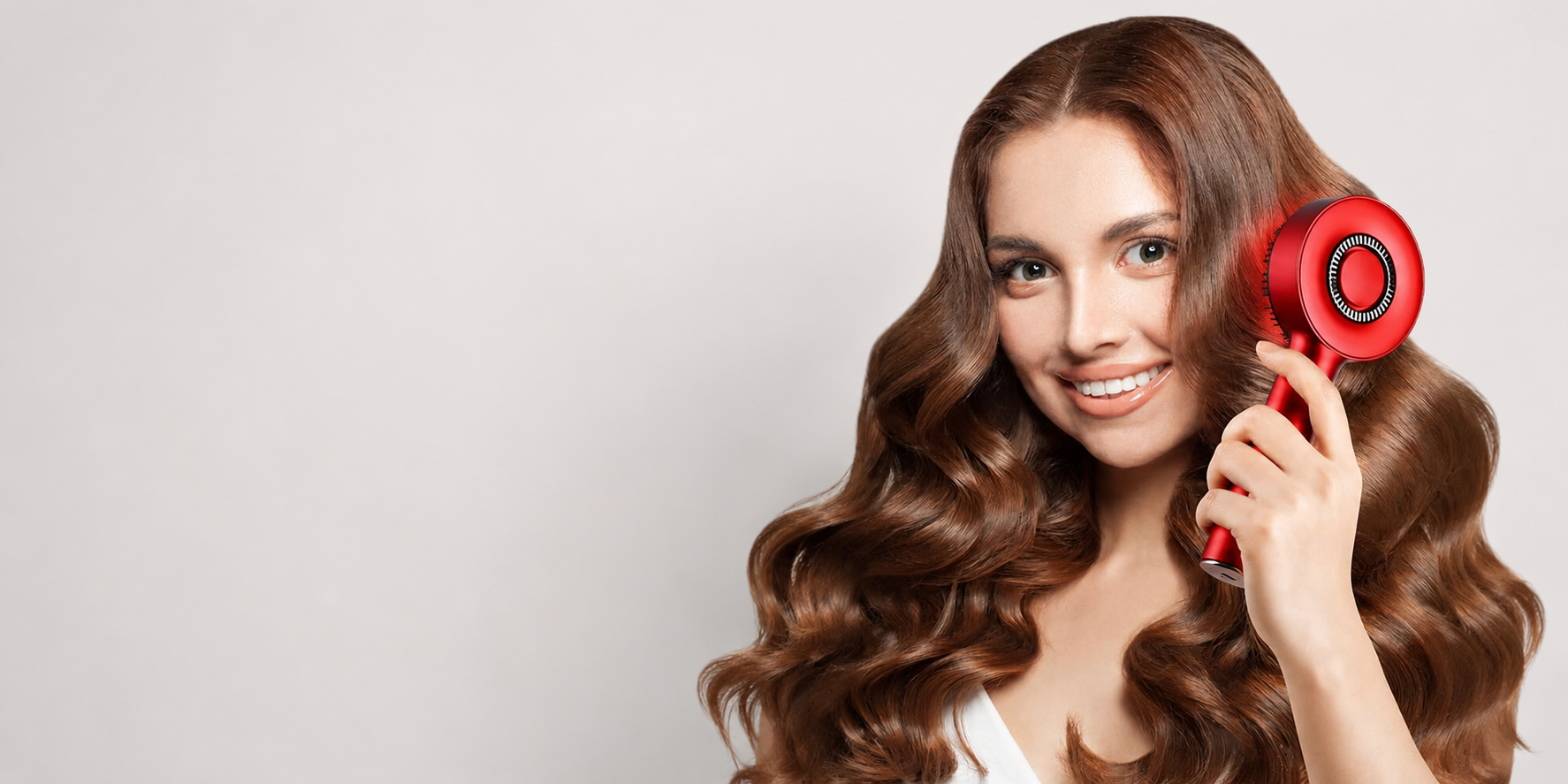 Woman with wavy hair using a red hairbrush on a light gray background
